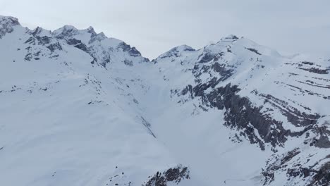 Aerial-drone-shot-capturing-the-silhouette-of-a-snowy-mountain-range-at-sunrise