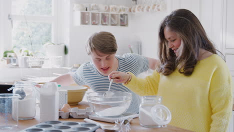 Junges-Down-Syndrom-Paar-Befolgt-Rezept-Auf-Digitalem-Tablet,-Um-Zu-Hause-In-Der-Küche-Kuchen-Zu-Backen