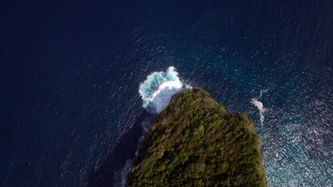 drone flying close forward close above kelingking beach on nusa penida island over the seashore green peninsula cliff ridge