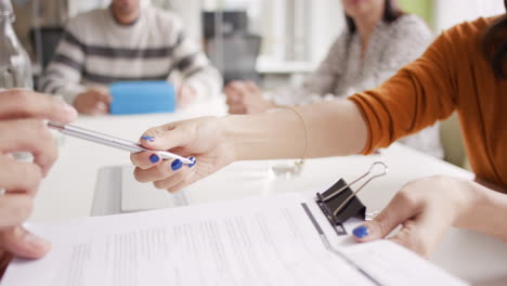 Female-executive-handing-over-partnership-agreement-Businessman-signing-contract-in-creative-modern-office-with-natural-light