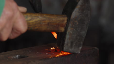 Close-up-of-an-incandescent-piece-of-metal,-hammered-on-the-anvil