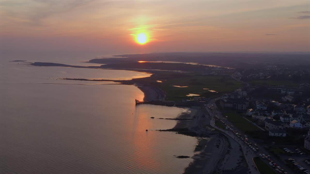 Aerial panoramic overview of golden sunset over Salthill Promenade, the Atlantic reflecting warm hues in Galway Ireland, static