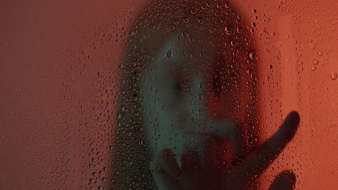 gotas de agua en una ventana con una silueta