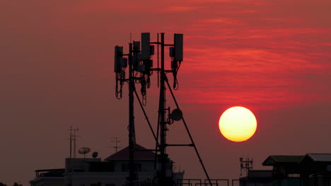 el lapso de tiempo de la puesta de sol en el cielo naranja con antenas celulares en el marco