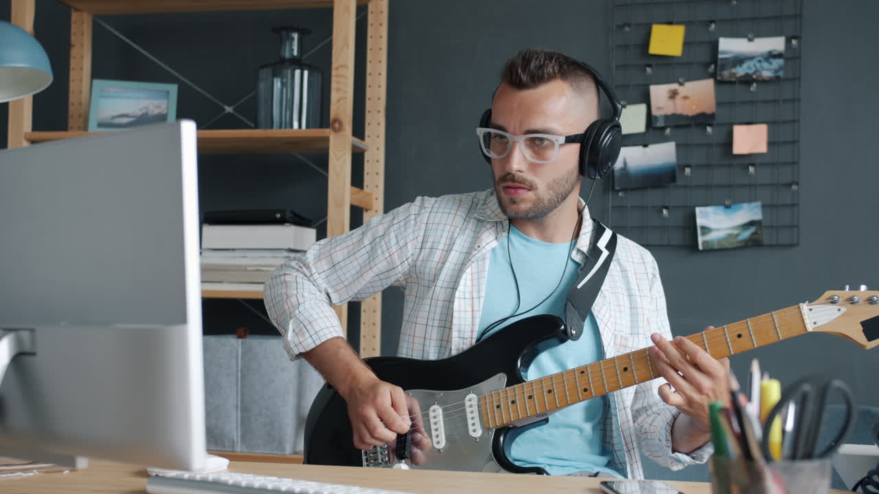 Man Playing Electric Guitar at Computer