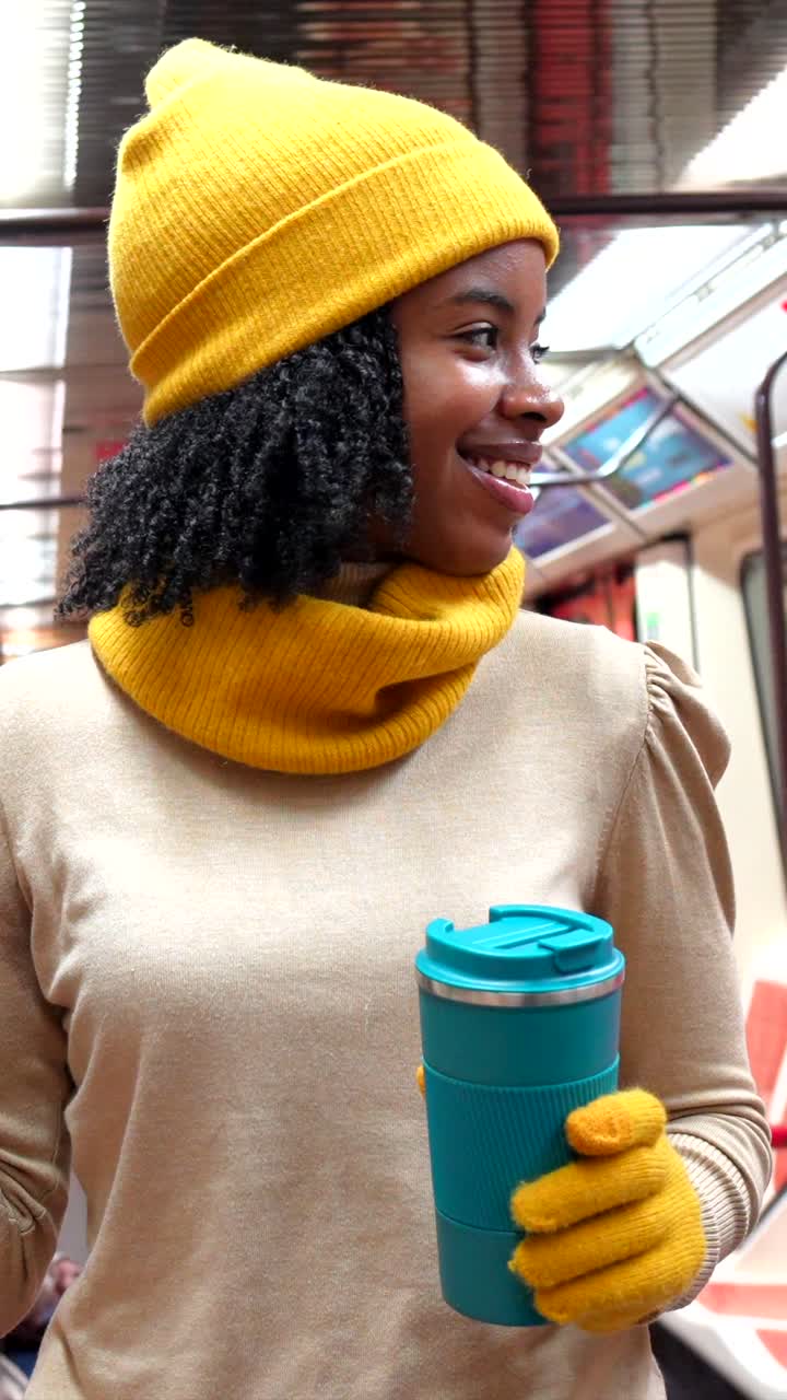 Woman in yellow hat and scarf holding a blue coffee cup