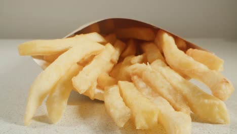 recogiendo a mano patatas fritas de un cono de papel