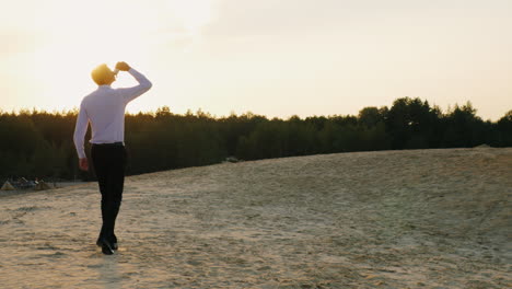 A-businessman-with-a-bottle-of-alcohol-walks-forward-on-the-sand-3