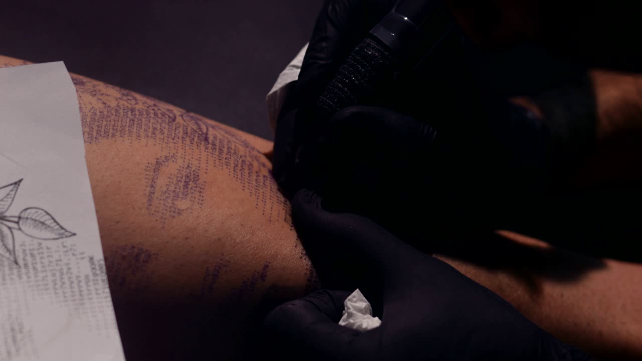 Tatuatore che usa una macchinetta per tatuaggi e disegna un motivo sulla pelle