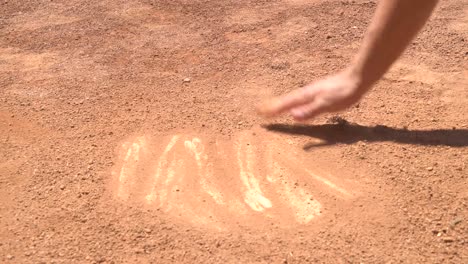 wiping dirt of home plate with hand