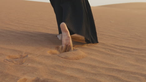 gros plan d'une femme musulmane méconnaissable marchant pieds nus dans le désert