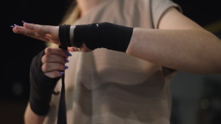 Unrecognizable woman preparing for fight at gym. Closeup woman wrapping hands