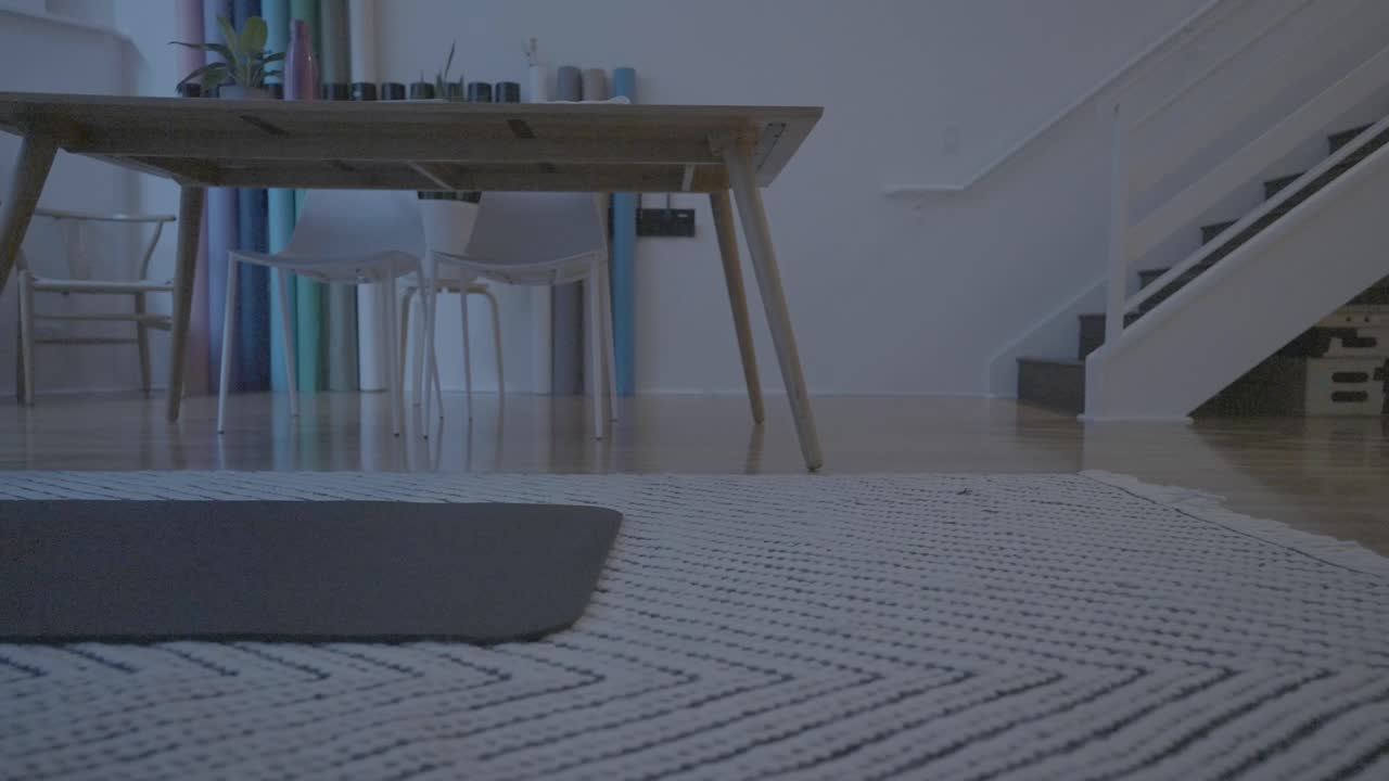 집에서 운동할 준비를 하기 위해 매트를 펴고 있는 여성