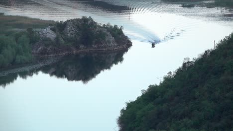 small passenger ship enters picture from above and leaves small waves in the water