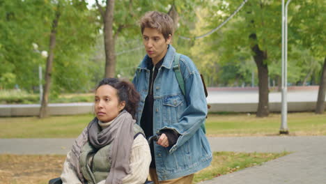 woman walking in park with friend in wheelchair