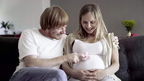 front view of happy couple sitting and playing with booties