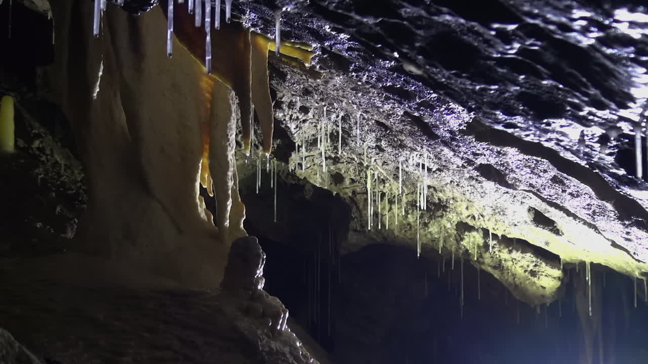 estalactita amarilla gotea agua sobre estalagmita debajo en una cueva profunda y oscura