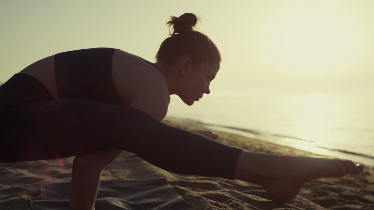 mujer profesional de yoga apoyada en las manos en posición de luciérnaga al atardecer de cerca.