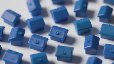 home buying concept with group of blue plastic models of houses revolving on white background