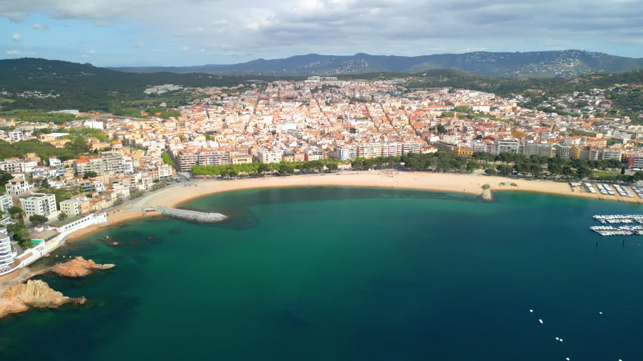 Aerial view showcasing the picturesque coastal town of sant feliu de guixols on the costa brava, spain, highlighting the vibrant cityscape nestled against the turquoise mediterranean sea