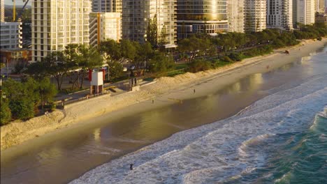 aerial view of gold coast beach at sunset, showcasing serene waves, sandy shores, and nearby high-rise buildings