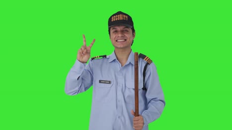 Fröhlicher-Indischer-Sicherheitsbeamter-Zeigt-Siegeszeichen-Auf-Grünem-Bildschirm