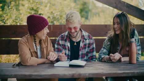 happy friends sitting with diary on table