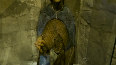 small religious doll holds figurine of christ child behind glass case