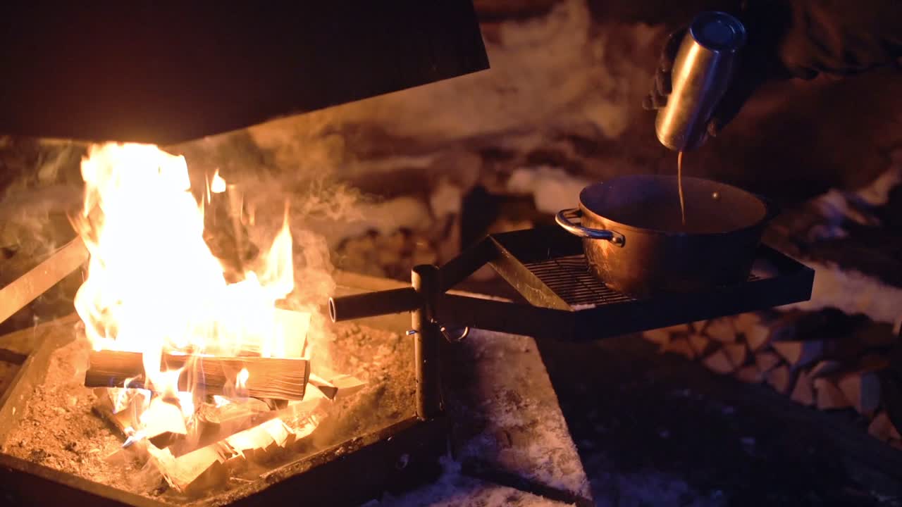 Pouring liquid into a pot over an outdoor fireplace, in Lapland, Finland