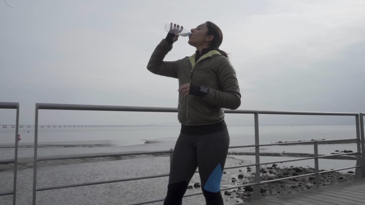 Giovane sportiva allegra che beve acqua dopo l'allenamento