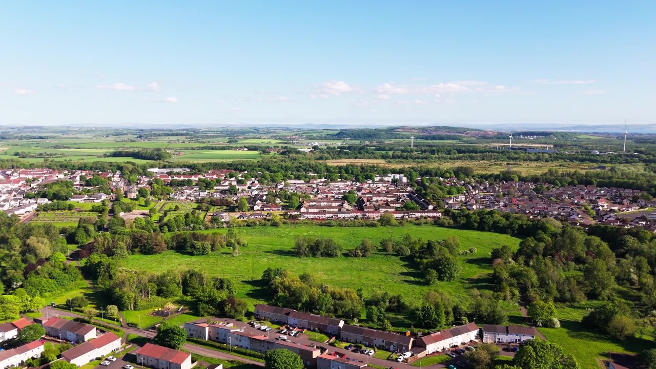 Bourtreehill Village, Irvine, North Ayrshire, Skotland, viser boligområder omgivet af skov, parkområder og åbent landskab, luftfoto med fremadgående dolly-bevægelse