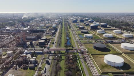 Oil refinery with natural gas storage tanks next to suburbs, aerial Argentina