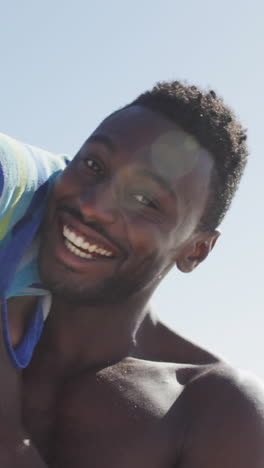 portrait of smiling african american father carrying his son on sunny beach