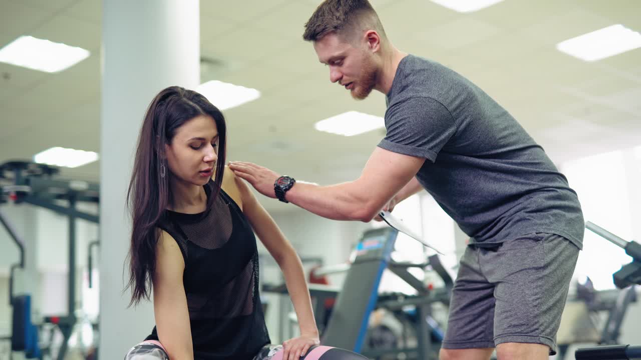 Young and beautiful woman working out with dumbbells in gym. Personal fitness instructor. Personal training.