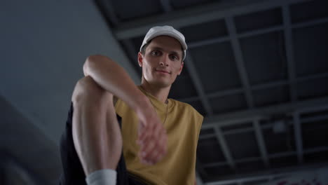 Attractive-man-resting-at-urban-skate-park.-Smiling-guy-gesturing-hand.