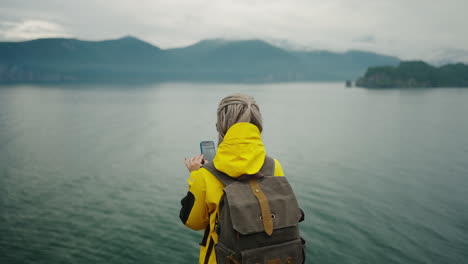 woman taking photo of scenic lake view