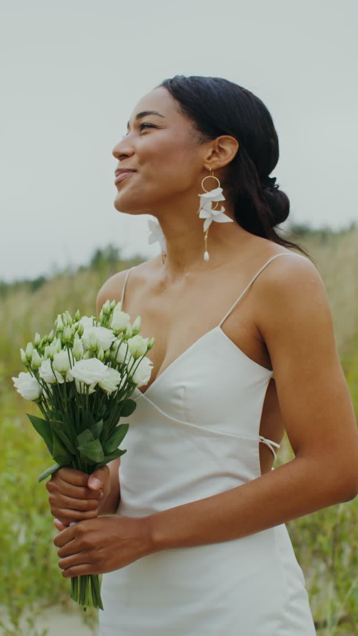 A bride holding a bouquet of white flowers in a field