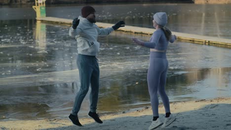una foto amplia de una pareja caucásica adulta calentándose antes de nadar en invierno.
