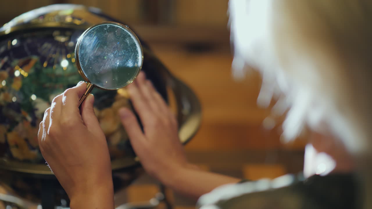 mujer con lupa en la mano examina la vista posterior del globo grande