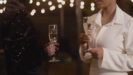 two elegant multiethnic women toasting and drinking champagne at new year's eve party