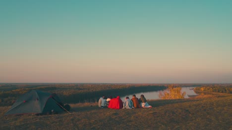 young-tourists-group-spends-time-at-burning-bonfire-by-river