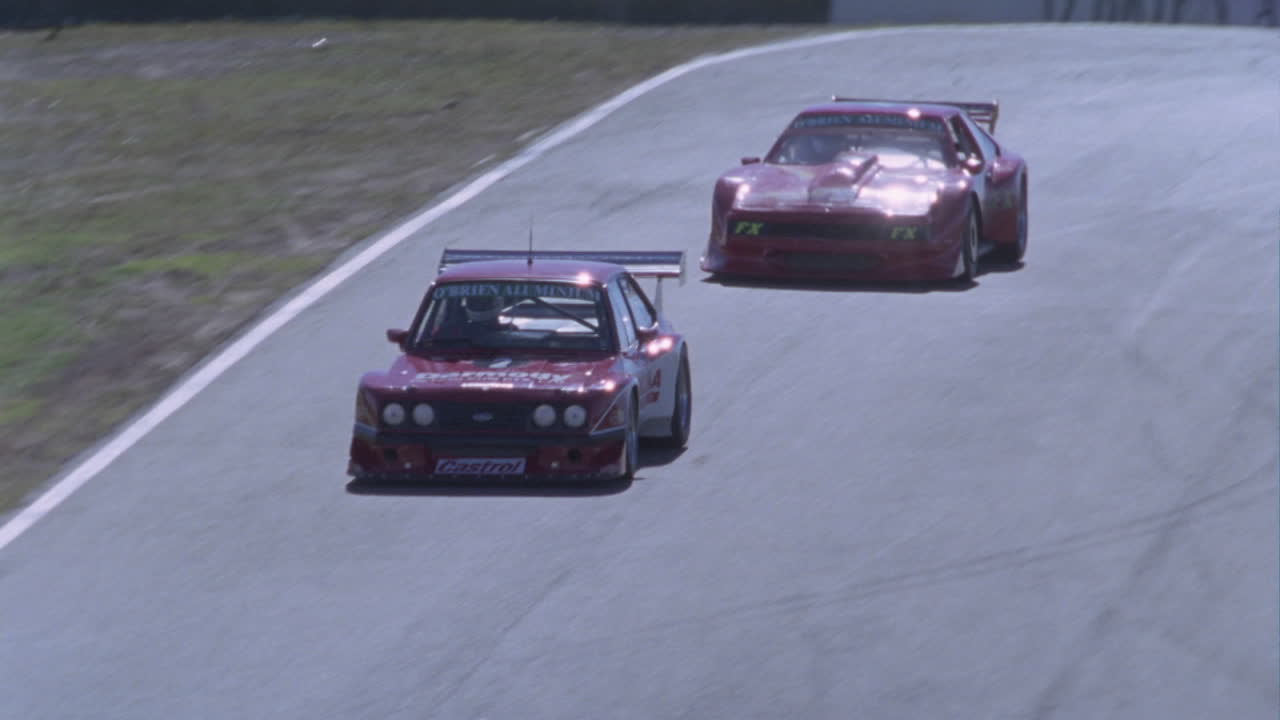 dos autos corren por una pista y se preparan para dar un giro brusco