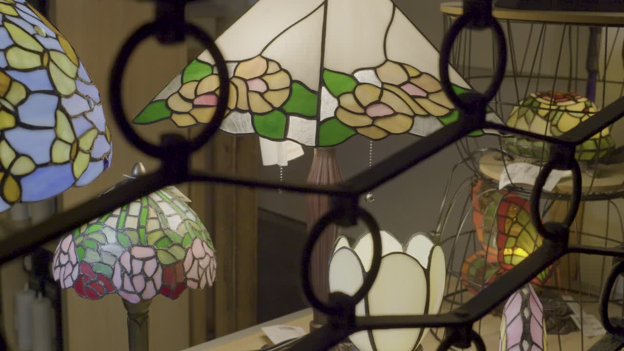 Vintage stained glass lamps on display with close-up details visible through a patterned frame