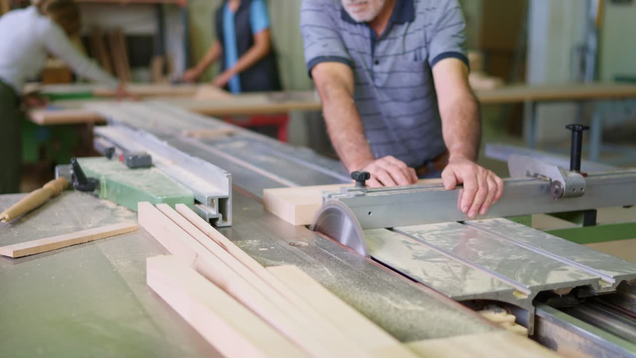 Falegname esperto che taglia il legno con una sega circolare in un laboratorio