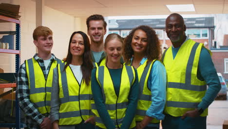 Porträt-Eines-Multikulturellen-Teams,-Das-Warnschutzkleidung-Trägt-Und-In-Einem-Modernen-Lager-Arbeitet