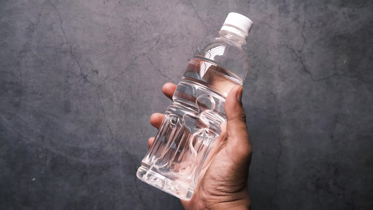 mano con una botella de agua de plástico transparente