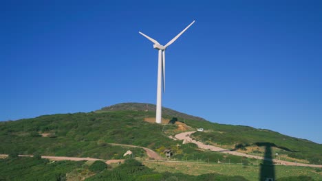 wind turbine on top of a hill with a clear blue sky in the background