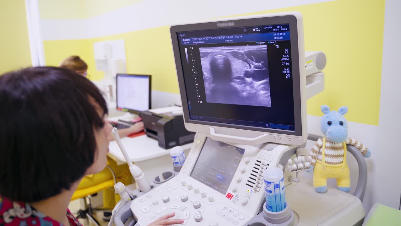 Woman doctor working with modern equipment in clinic. Specialist looking at the screen of monitor during ultrasound diagnostic.