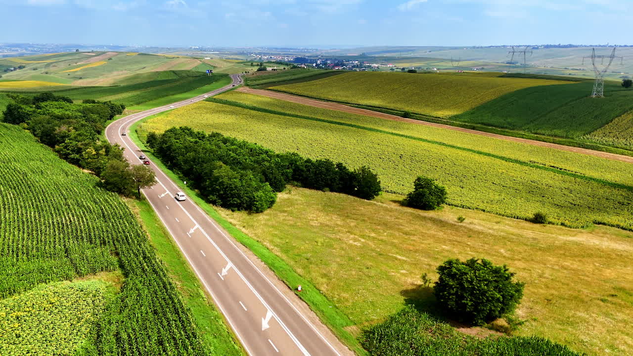 Green fields and highway sky. Rolling hills covered in lush greenery border a winding highway
