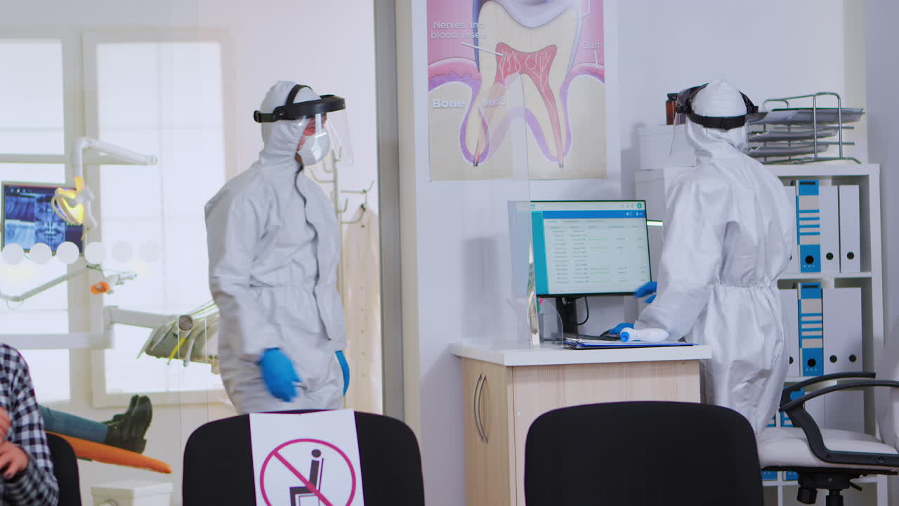 médico dental con traje de ppe sosteniendo rayos x de los dientes